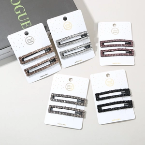 Close-up of five pairs of handmade rhinestone hair clips in various colors on display cards