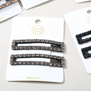 Detail view of handmade rectangular hair clips featuring sparkling grey rhinestones