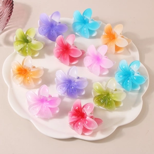 Flat lay of 12 colorful frangipani flower hair claws in a matte resin finish