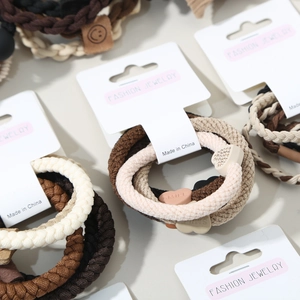 Detailed macro view of five woven elastic hair ties with heart shaped smile buckles