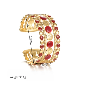 Dettaglio del bracciale vintage dorato traforato con smalto rosso e motivi floreali