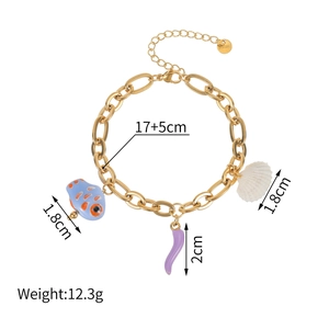 Détail d'un bracelet en acier doré avec pendentifs poisson en céramique et piment