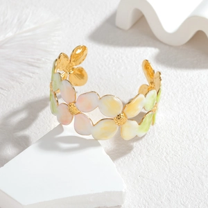 Detailed close-up of a floral enamel open bangle with a luxury gold metal base