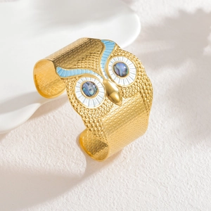 Artistic golden owl cuff bracelet with blue enamel inlay and iridescent shell eye detail