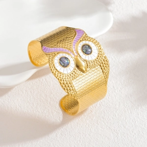 Detail view of golden owl cuff bracelet with purple enamel and abalone shell eyes