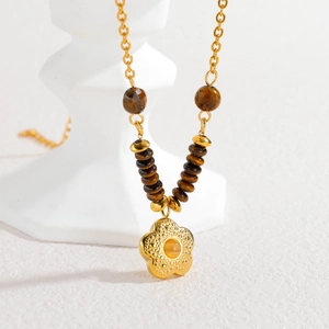 Tiger eye beaded necklace with a golden flower pendant on a minimalist white base