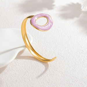 Detail of a minimalist gold C-shaped cuff bracelet with light purple enamel drop ornament