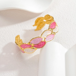 Elegant gold leaf open bangle with pink and white enamel coating on stone backdrop