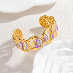 Detail view of gold hollow circular links with purple and white enamel inlay on the bangle