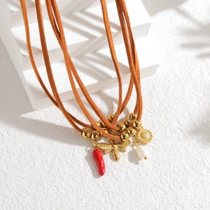 Détail du collier multi-rangs en daim marron avec breloques abeille et piment rouge