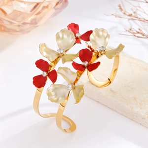 Detail view of gold floral bangle featuring red and cream enamel petals with cubic zirconia