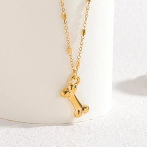 Elegant gold stainless steel necklace with bone pendant and square bead chain on white stand