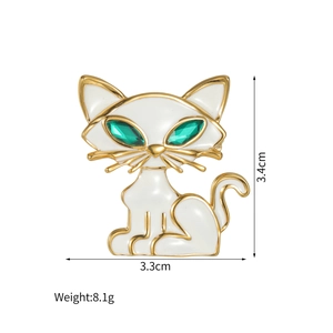 Détail d'une broche chat en émail blanc avec bordure dorée et dimensions 3,4cm x 3,3cm