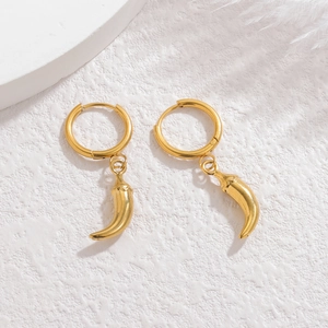 Golden hoop earrings featuring a polished chili pepper pendant on a white textured background