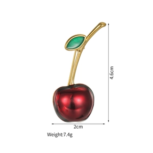 Vue détaillée de la broche cerise rouge avec tige dorée, dimensions 4,6 cm par 2,0 cm