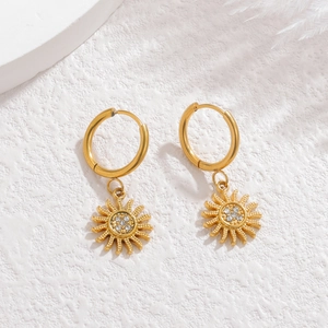 Golden sun-shaped hoop earrings featuring sparkling crystal rhinestones on a white background