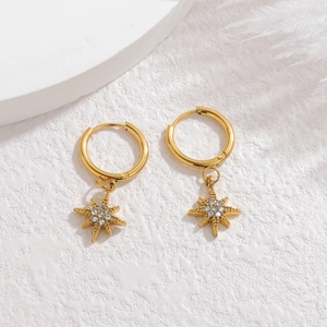Macro shot of gold hoop earrings featuring star pendants with sparkling inlaid crystals