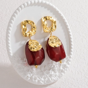 Detail of hammered gold metal texture and deep red glass pendant on vintage earrings
