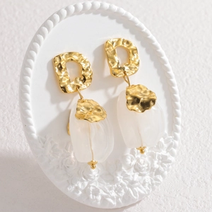 Elegant gold tulip earrings with white glass petals on a white relief display stand