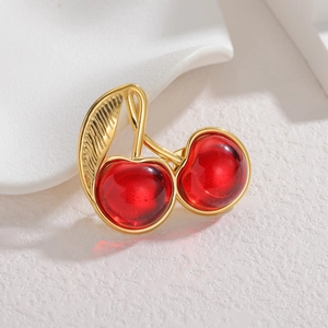Vue détaillée de la broche cerise avec feuilles dorées et fruits en résine rouge