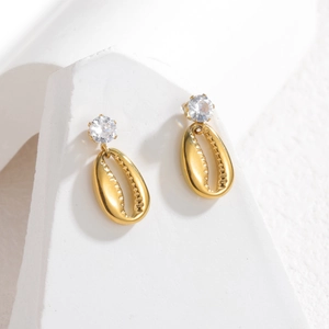 Detail of gold shell earrings featuring clear zircon stud and intricate inner textures