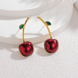 Detail view of cherry earrings with glossy red glaze and gold metal stems on a white stand
