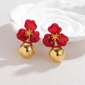 Detail of red enamel flower earrings with a polished golden sphere pendant