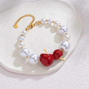 Détail du bracelet en perles avec pendentifs cerises rouges sur plateau en céramique