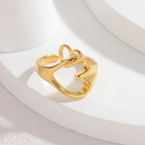 Bague ouverte double cœur minimaliste dorée sur un socle géométrique blanc