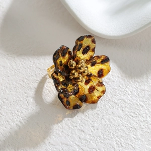Macro shot of leopard print resin flower ring with golden beads on white stone surface