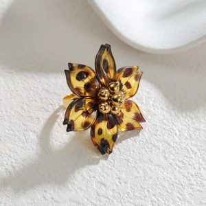 Elegant resin leopard print flower ring with gold beads on a white textured surface