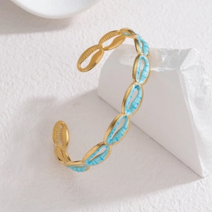 Gold-plated stainless steel bangle featuring sky blue enamel oval links on a white stone