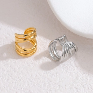 Detailed view of minimalist gold and silver stacked hollow ear cuffs on stone surface