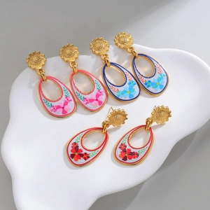 Retro sunflower teardrop earrings in pink, blue and red on white ceramic tray