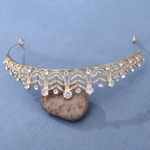 Detailed macro view of the gold bridal crown with crystal leaf patterns on a blue background