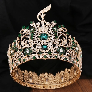 Detailed close-up of golden baroque tiara with green emerald stones and white zircons