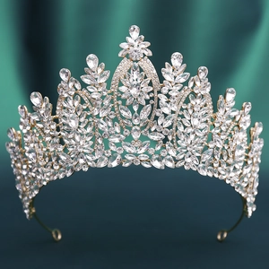 Detailed close-up of golden baroque crown with sparkling crystals on green velvet