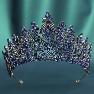 Detail of vintage gold crown with deep blue crystals on dark green fabric backdrop