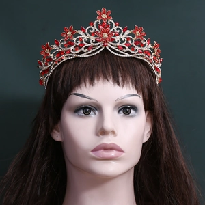 Couronne de mariée dorée avec cristaux rouges et motifs floraux sur support d'exposition