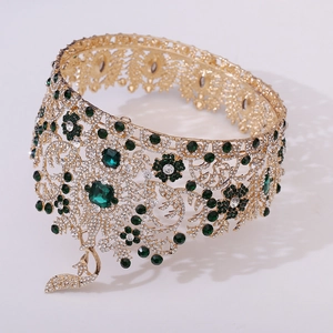 Detailed macro view of baroque gold crown with green gems and intricate bird pendant
