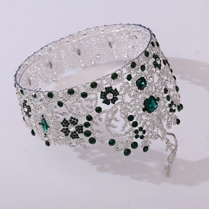 Detail of royal silver crown with emerald green stones and intricate diamond patterns