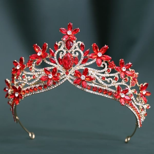 Macro shot of gold floral bridal crown with red crystals on a dark green fabric