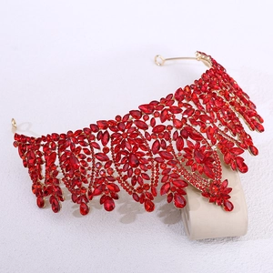Close-up of golden bridal tiara with red marquise crystals on a minimalist pedestal
