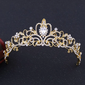 Macro detail of golden baroque crown featuring white rhinestones and large teardrop crystal