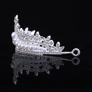 Sparkling silver bridal crown with crystals and pearls on a sleek black reflective background