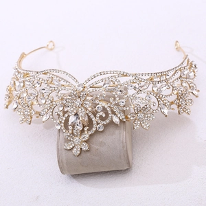 Gros plan d'une couronne de mariée dorée avec des cristaux sur un support velours