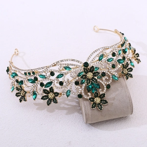 Détail de couronne baroque dorée avec gemmes vert foncé et strass blancs brillants