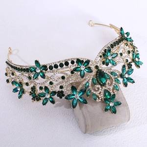 Macro detail of Baroque bridal crown with emerald green crystals and golden floral patterns