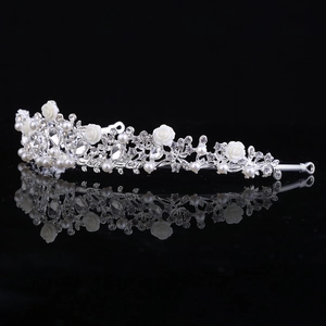 Dettaglio corona da sposa in argento con rose bianche, perle e strass brillanti su fondo nero