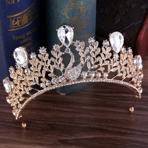 Détail de la couronne baroque de cygne dorée avec strass blancs sur livres anciens